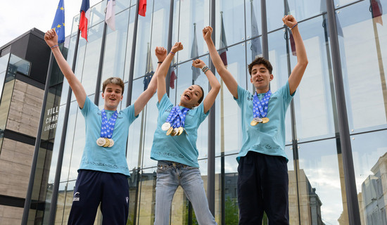 Trois jeunes sautant les bras en l'air avec leurs médailles autour du cou