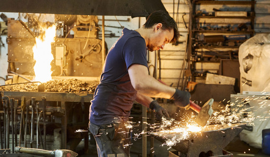 Un forgeron des Ateliers Templier martelant sur une enclume