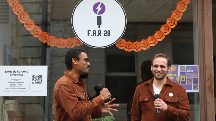 Deux jeunes hommes avec des micros dans les mains chantant devant la vitrine du karaoké F.A.R. 28