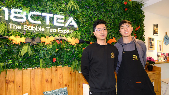 Deux jeunes hommes en tablier dans un salon de thé moderne proposant du bubble tea