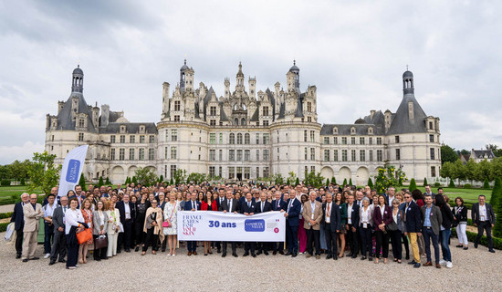 Un groupe tenant une banderole célébrant les 30 ans de la Cosmetic Valley, devant le chateau de Chambord