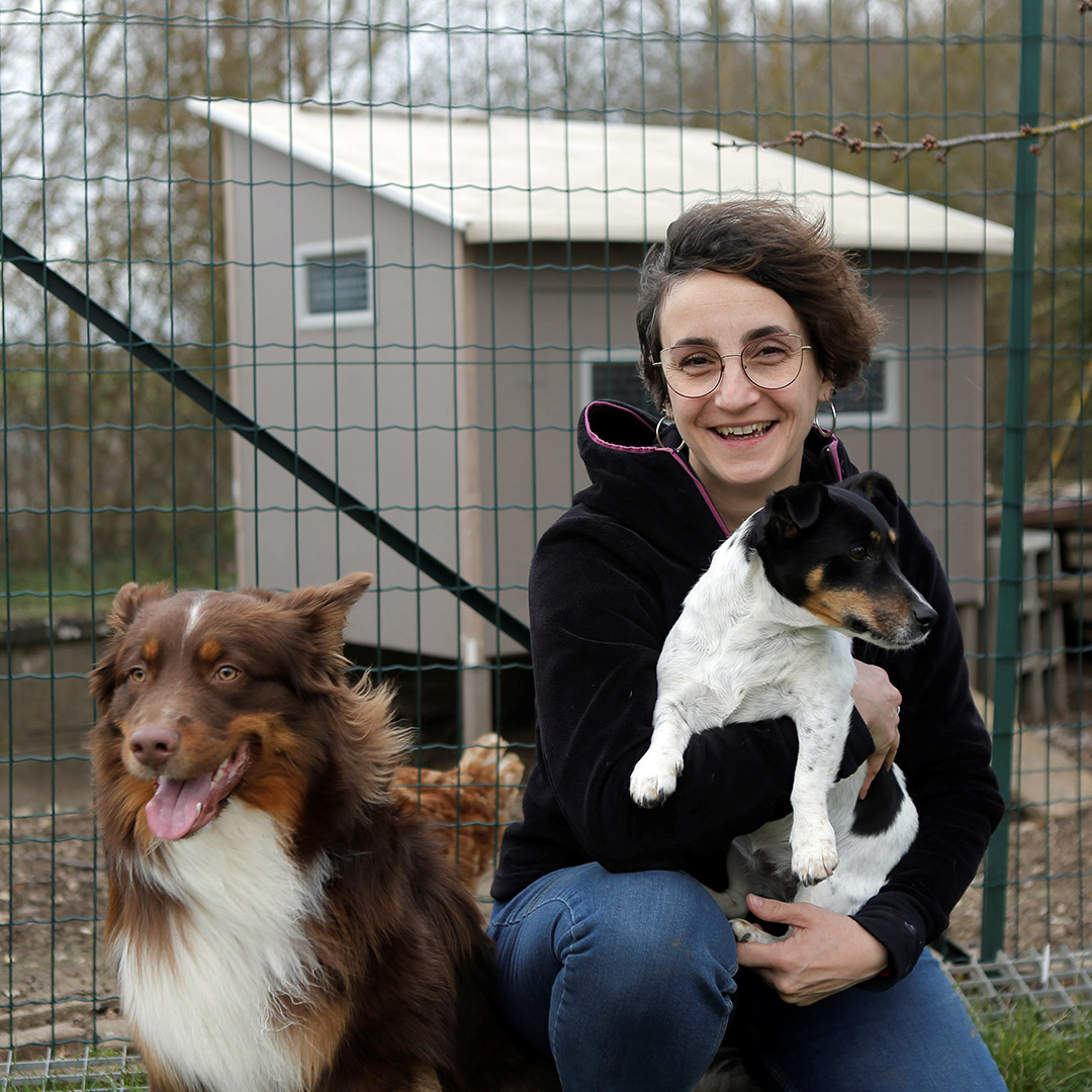 Femme tenant dans le bras un chien et se tenant à côté d'un autre, plus grand