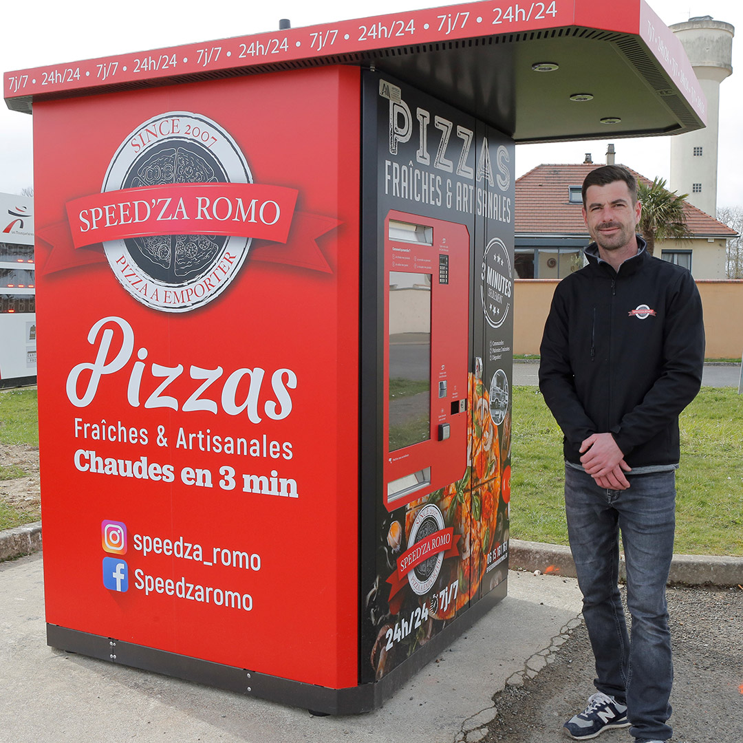 Homme se tenant près d'un distributeur rouge de pizzas